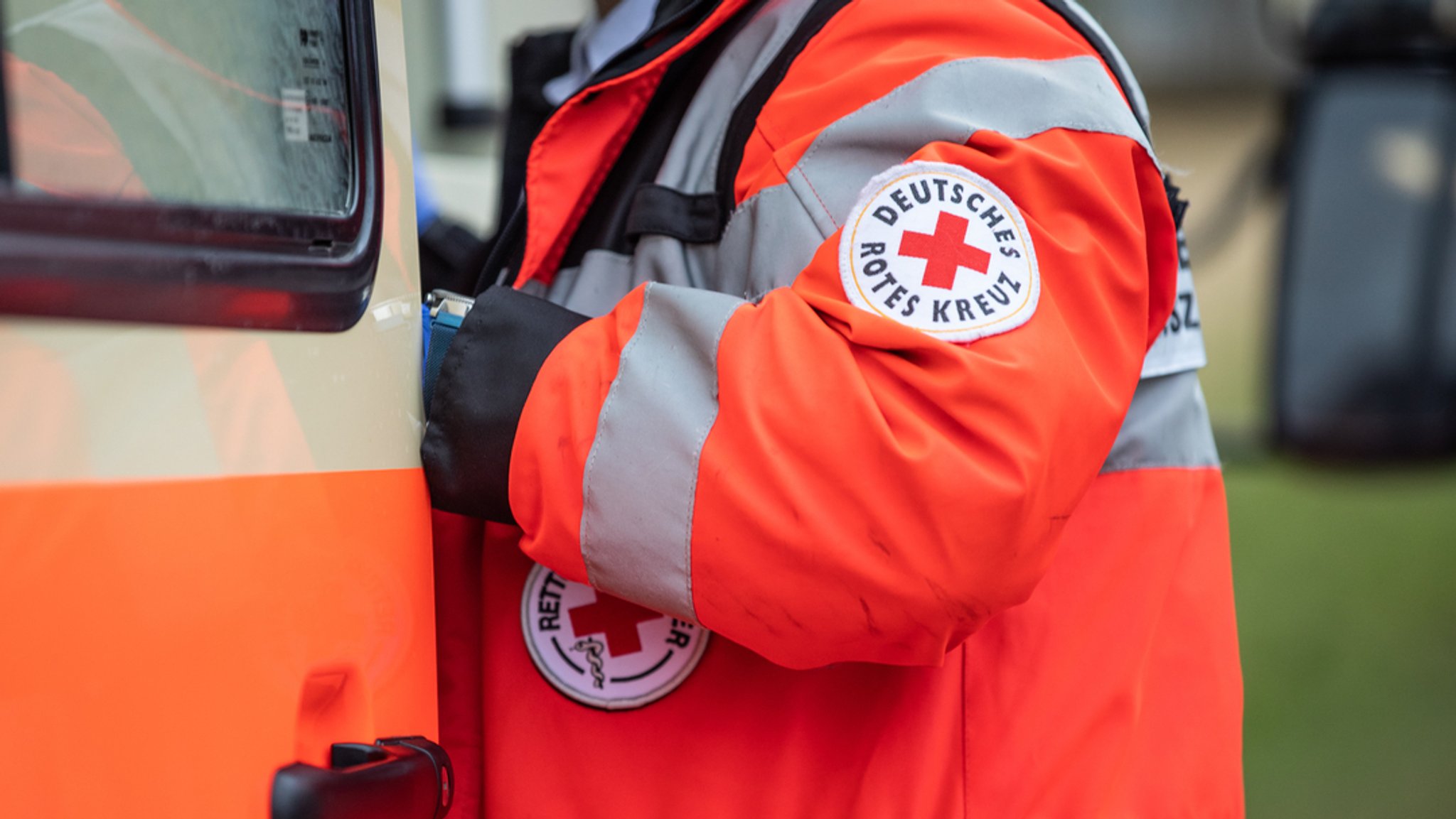 Ein Sanitäter steht am Krankenwagen.