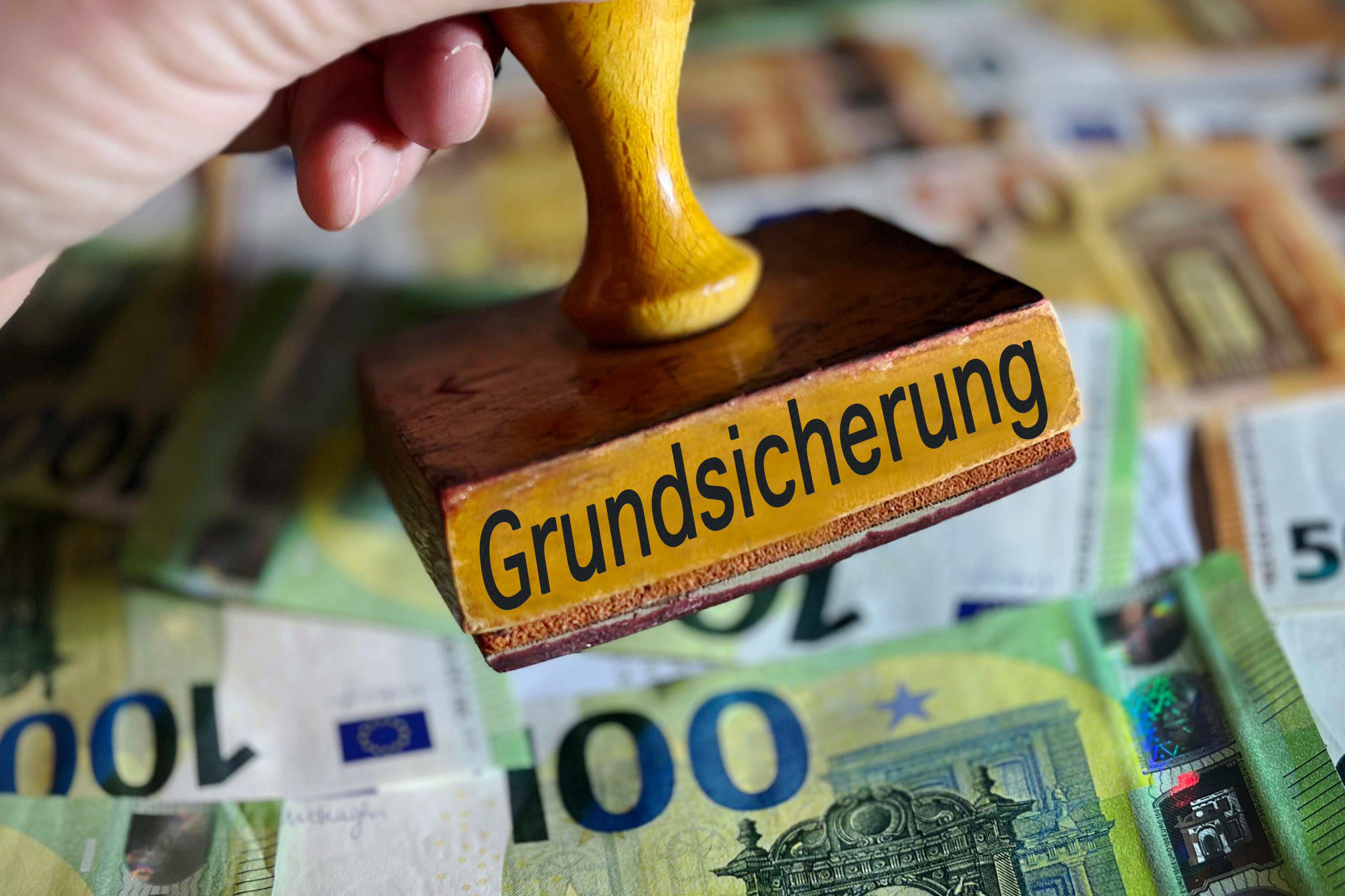 Geldscheine über denen eine Behördenstempel droht (Symbolbild)