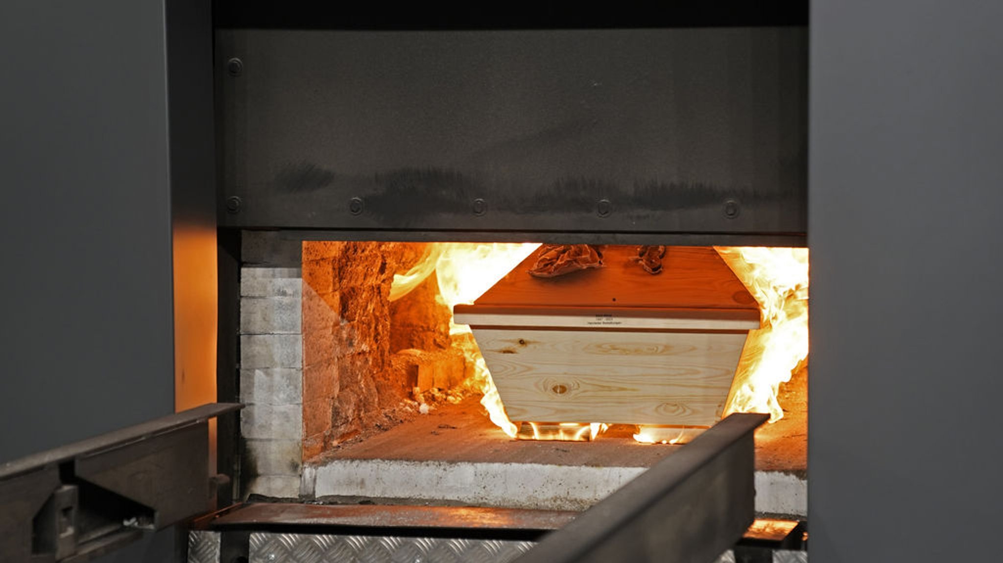 28.11.2023, Bayern, Traunstein: Ein Sarg wird in der von der EHG Dienstleistung GmbH betriebenen Feuerbestattungsanlage Traunstein in den Ofen gefahren. Zahlreiche operative und bauliche Maßnahmen wurden ergriffen, um einen Betrieb der Feuerbestattungsanlage ohne zusätzliche Emission von gebundenem CO2 zu ermöglichen. Foto: Uwe Lein/dpa +++ dpa-Bildfunk +++