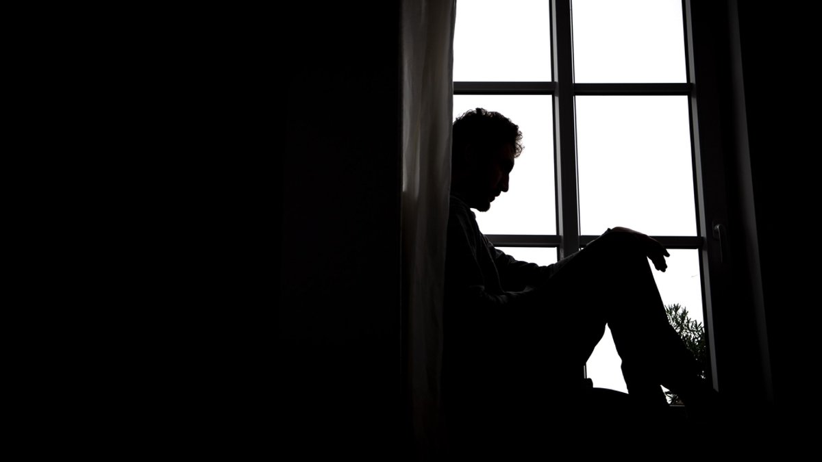 Ein junger Mann sitzt am Fenster (Symbolbild)