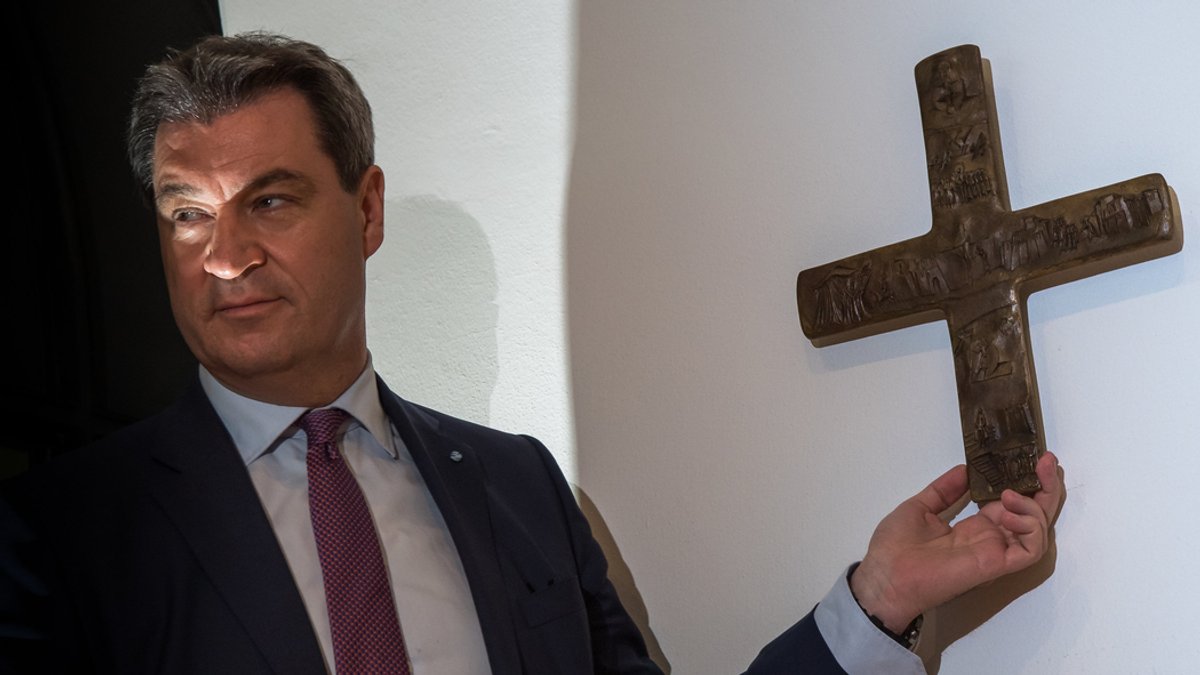 Markus Söder, Bayerischer Ministerpräsident (CSU), hängt ein Kreuz im Eingangsbereich der bayerischen Staatskanzlei auf. (2018)