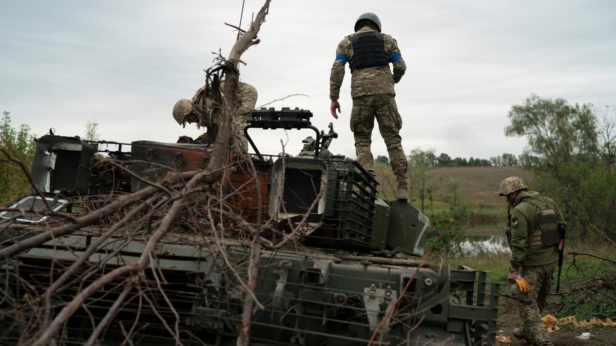Ukrainische Soldaten stehen auf einem zerstörten russischen Panzer in einem zurückeroberten Gebiet nahe der Grenze zu Russland in der Region Charkiw.