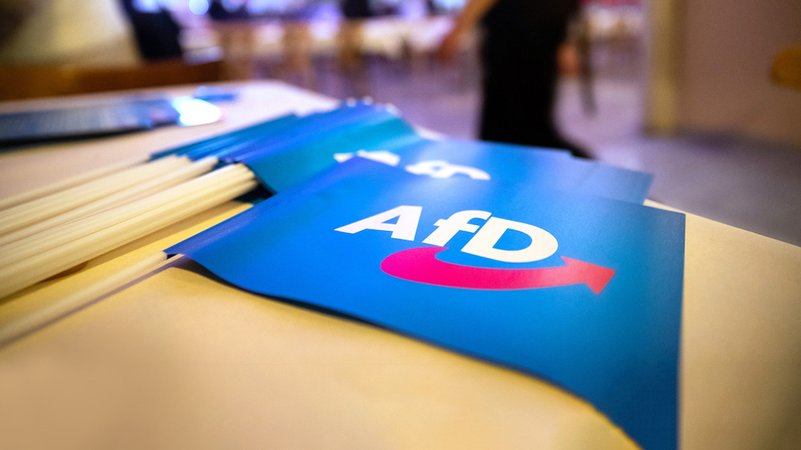 Papierfähnchen mit dem Logo der AfD liegen auf einem Tisch an einem Landesparteitag. | Bild: BR24TV/picture alliance/Daniel Karmann Papierfähnchen mit dem Logo der AfD liegen auf einem Tisch an einem Landesparteitag.