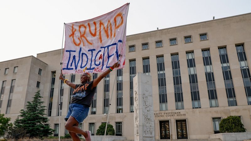 Eine Frau freut sich über die erneute Anklage Trumps und hält vor dem Gerichtsgebäude ein Transparent hoch: "Trump angeklagt".