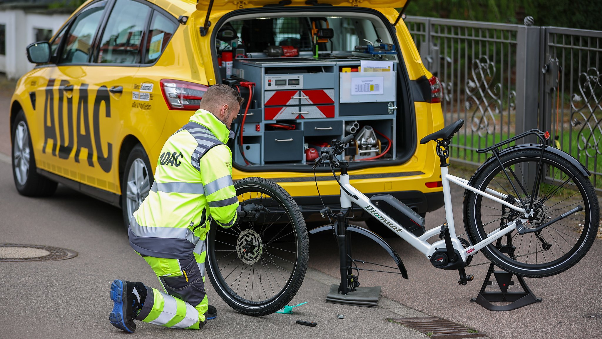 Ein ADAC-Pannenhelfer leistet Pannenhilfe an einem E-Bike.