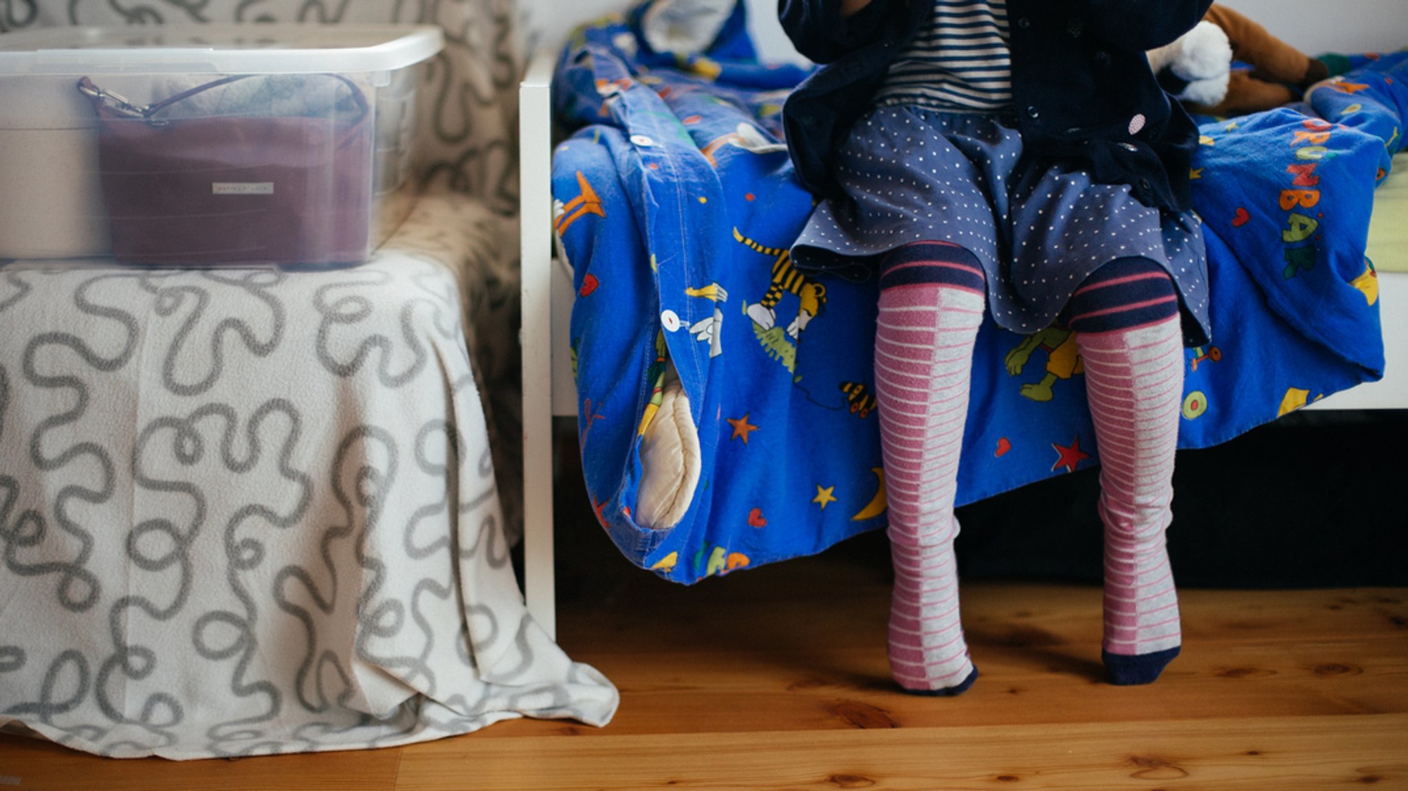 Ein Kind sitzt im Kinderzimmer auf dem Bett.