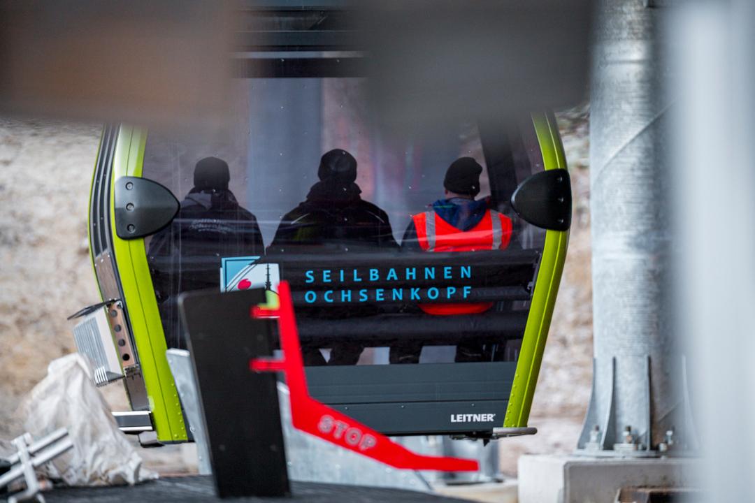 Drei Personen fahren in einer Gondel der neuen 10er Einseil-Kabinenumlaufbahn von der Talstation Nord zur Bergstation des Ochsenkopfs. 