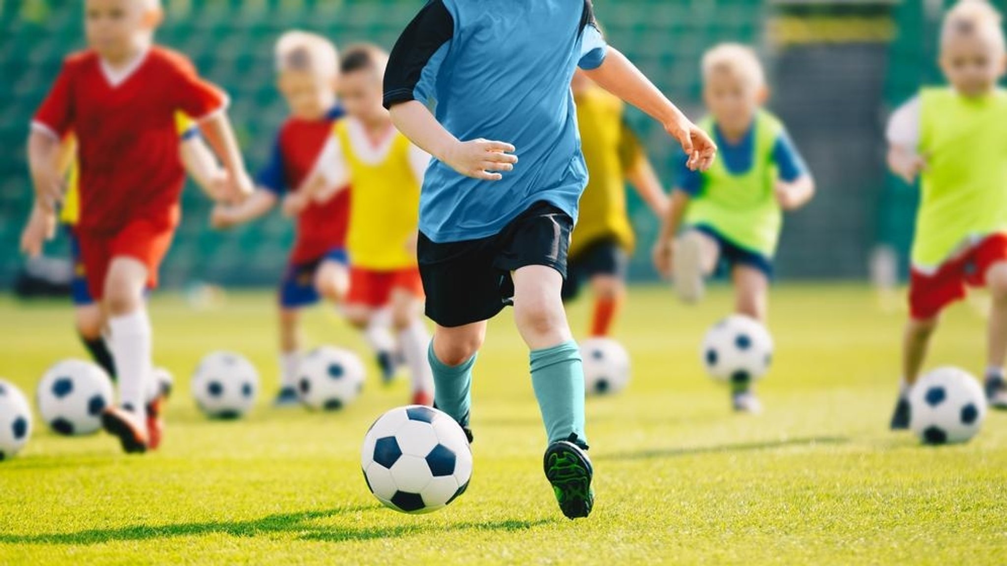 Eine Gruppe Jungen trainiert mit Fußbällen auf einem Fußballplatz.