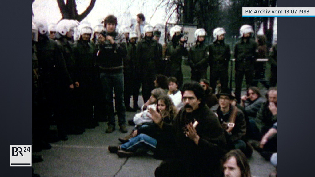 Sitzende Demonstranten umringt von Polizisten