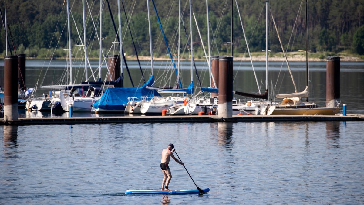 Fränkisches Seenland Yachthafen Ramsberg: Ein Mann gleitet mit einem Stand-Up-Paddle über den Brombachsee.