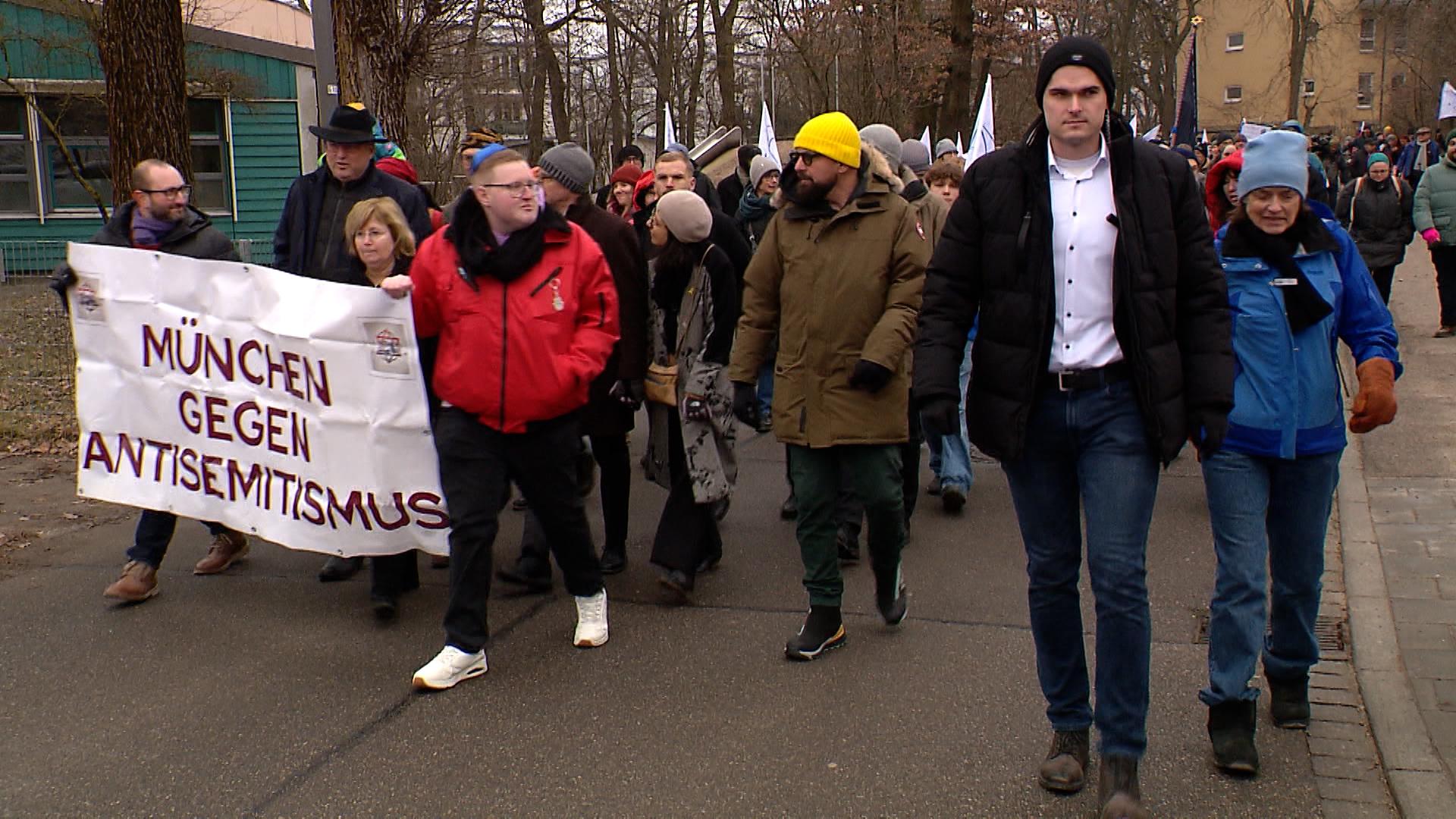 Teilnehmer des "March of the living" laufen mit Plakaten und Fahnen eine Straße entlang.