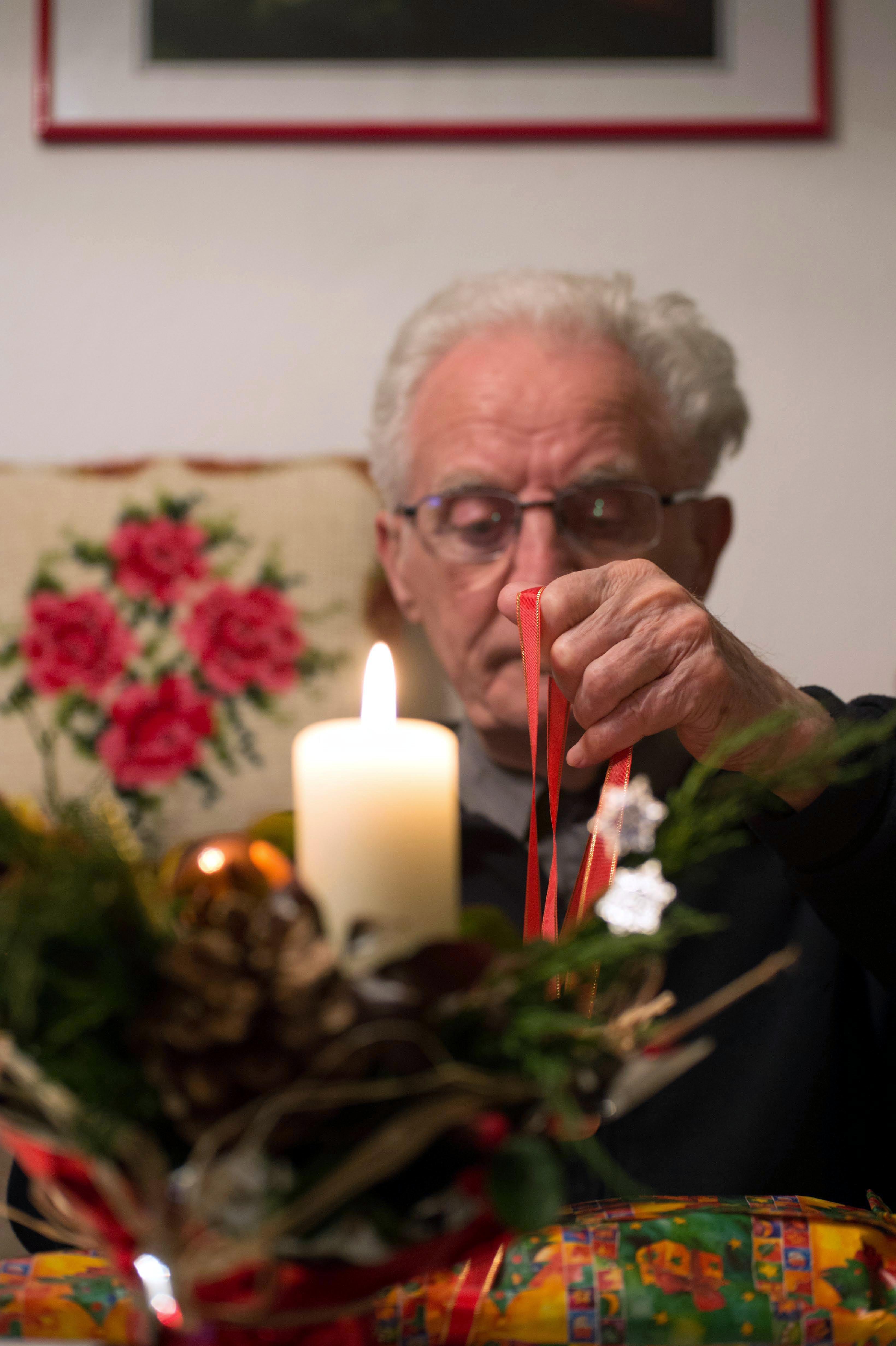 Mann sitzt allein vor einer Kerze.