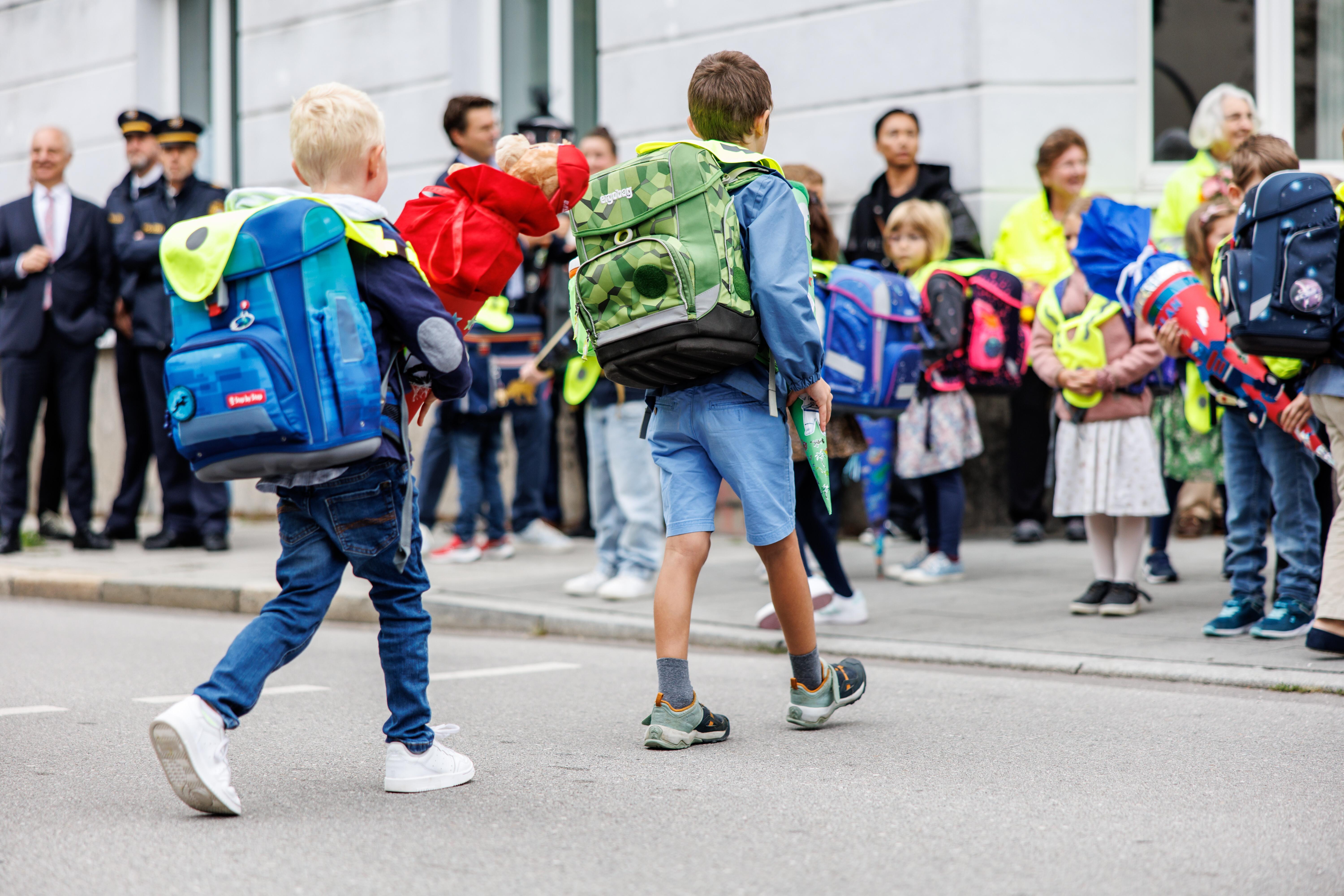 Zwei Erstklässler überqueren mit Ranzen und Schultüte die Straße