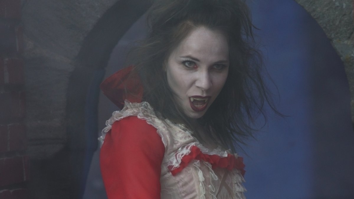 Eine Schauspielerin auf der Bühne öffnet ihren Mund und zeigt ihre spitzen Vampirzähne.
