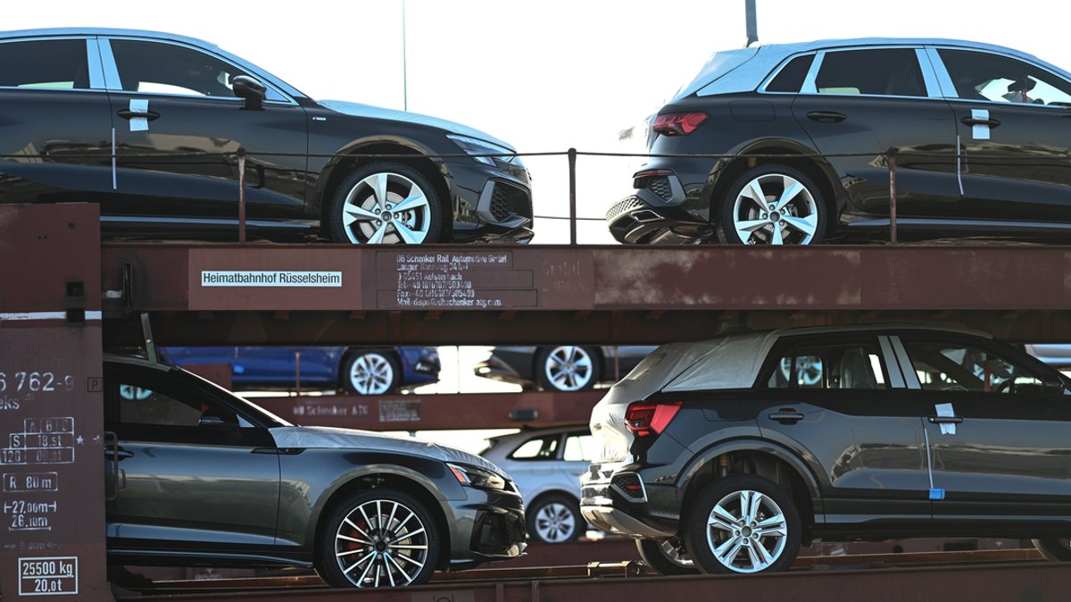 Neuwagen von Volkswagen und Audi stehen auf einem Autozug in einem Hafen.