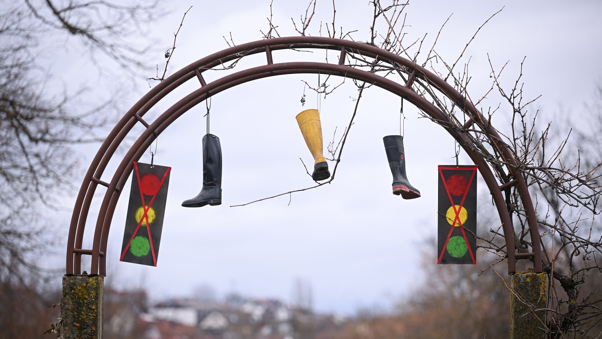 Ampel und Gummistiefel hängen an einem Torbogen.