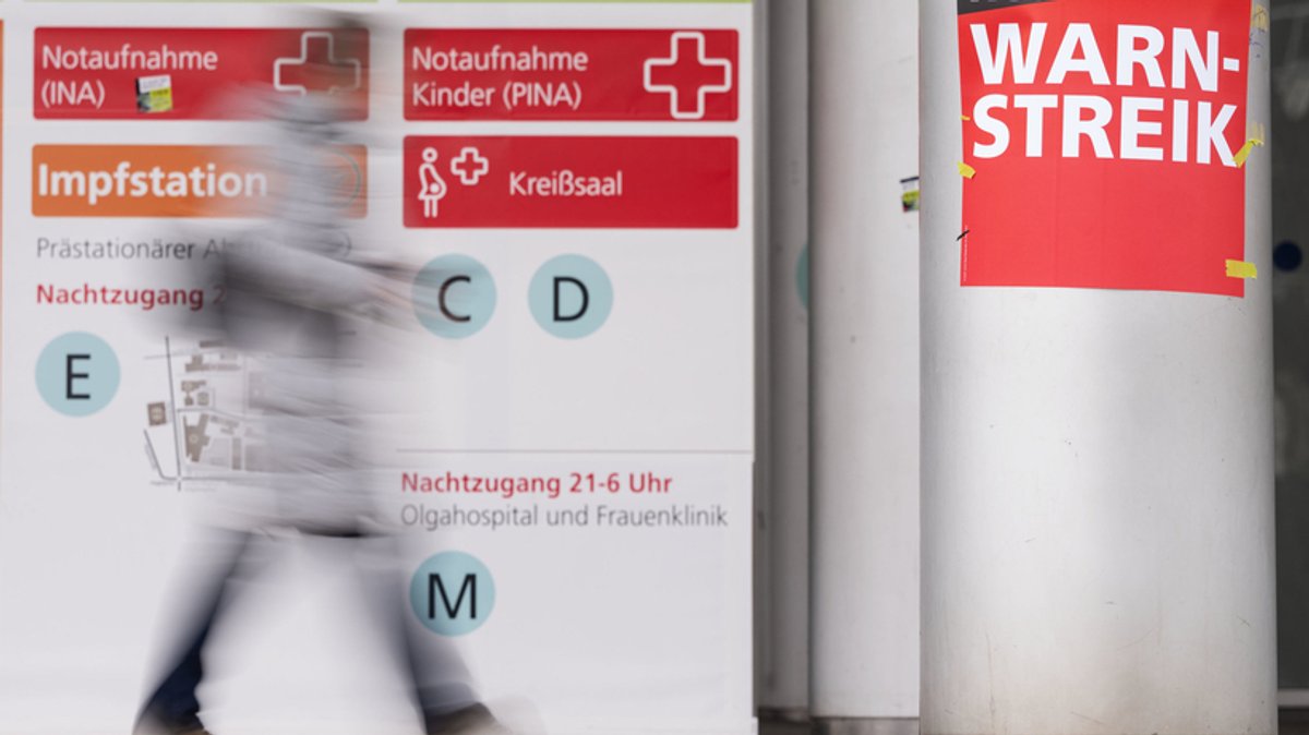 Schilder mit der Aufschrift ·Warnstreik· hängen am Eingang eines Krankenhauses.