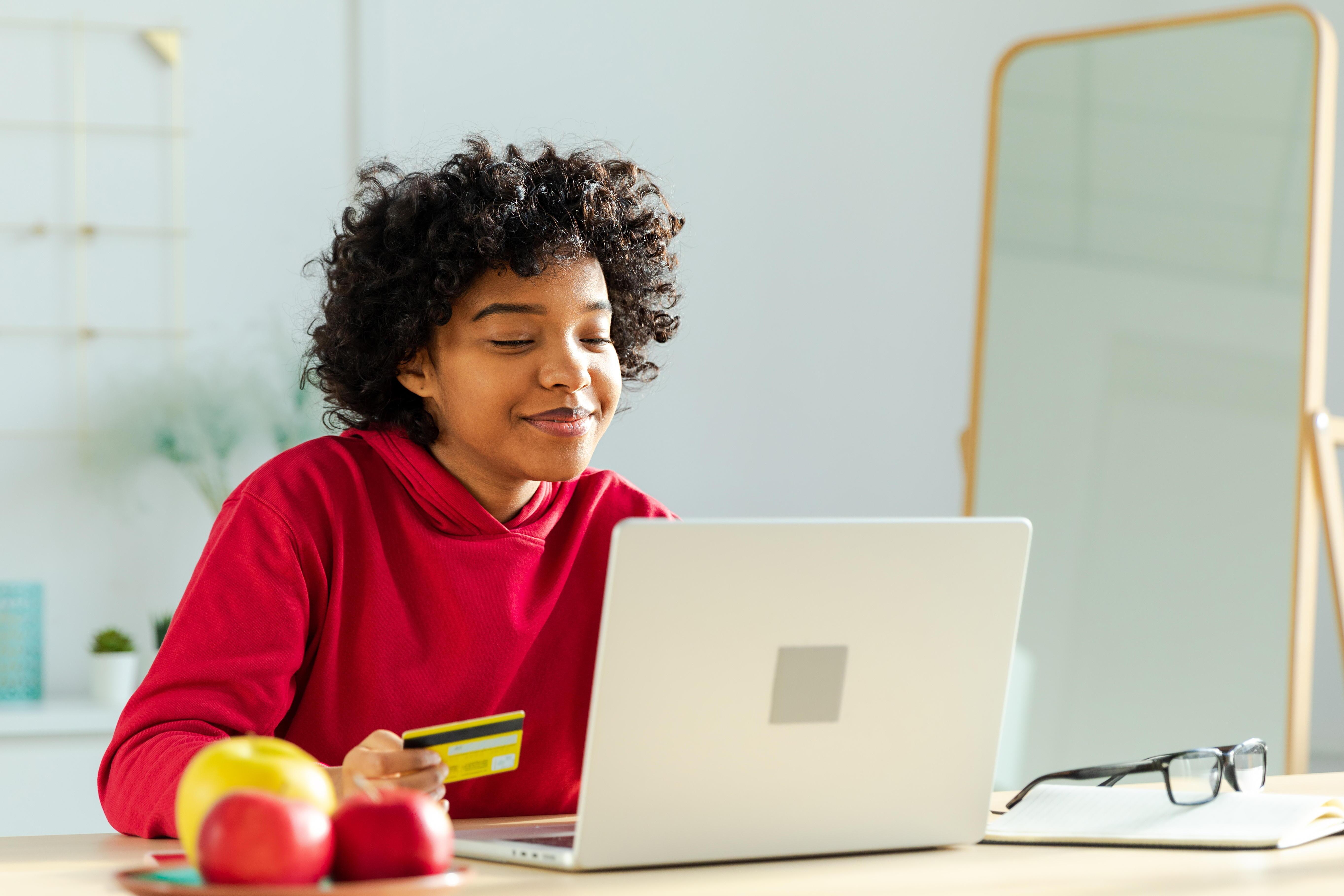 Junge Frau am Laptop beim Online-Shopping mit Kreditkarte