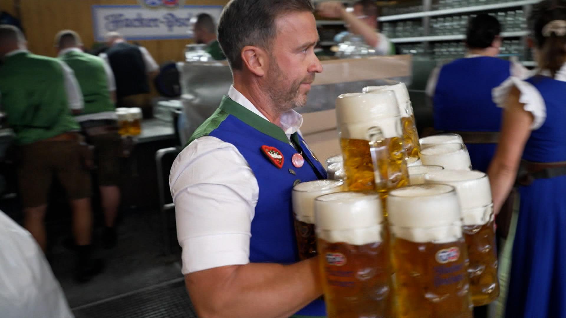 Kellner trägt Maßkrüge durchs Zelt