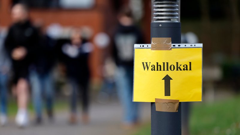 Ein Zettel weist den Weg zu einem Wahllokal. (Symbol Bild) | Bild: picture alliance / Panama Pictures | Christoph Hardt Ein Zettel weist den Weg zu einem Wahllokal. (Symbol Bild)