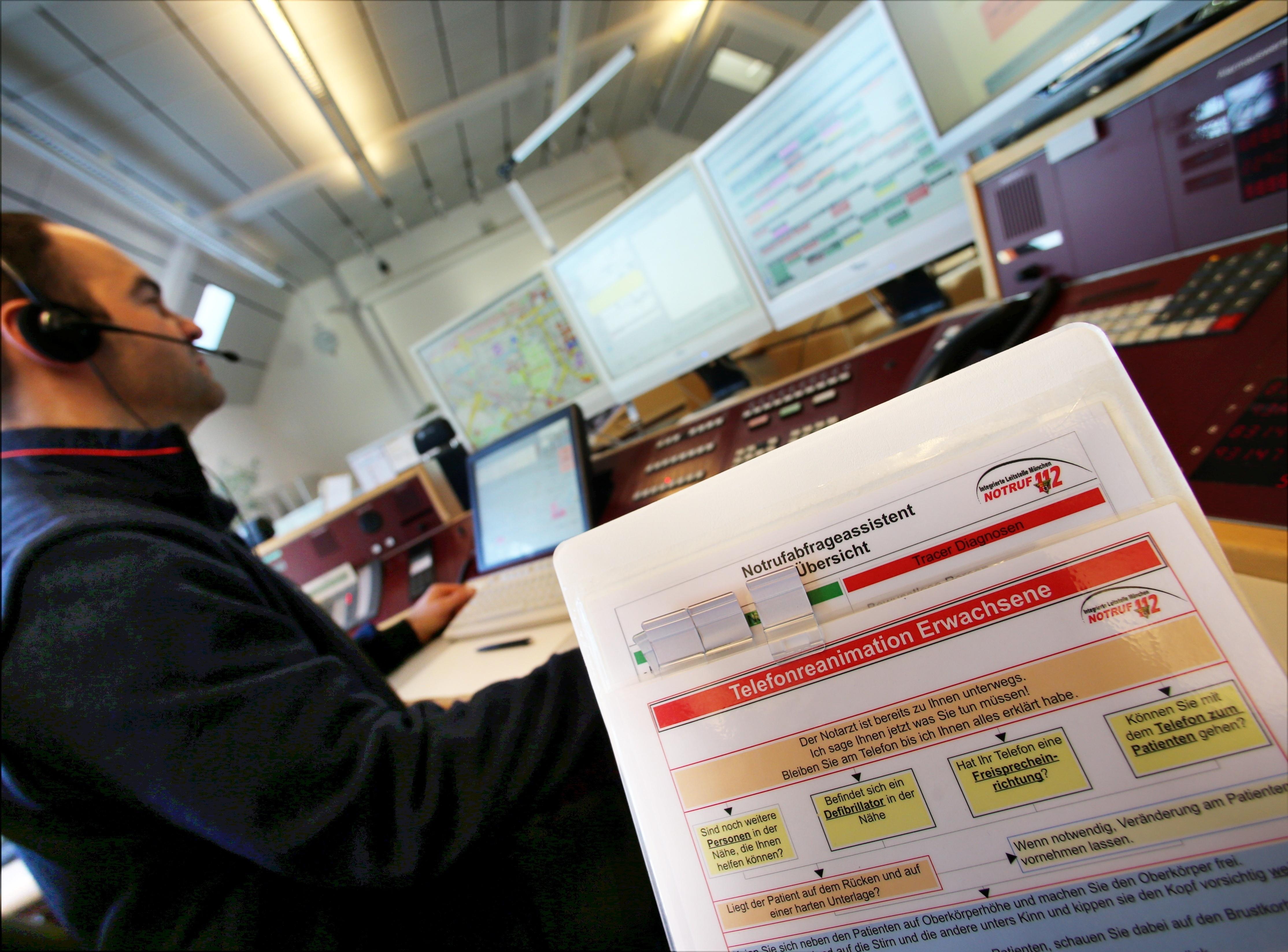 Ein Mann sitzt in der Integrierten Leitstelle. Im Vordergrund eine Anleitung für eine Telefonreanimation.