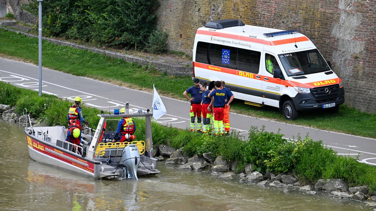 03.08.2024, Baden-Württemberg, Ulm: Einsatzkräfte suchen am Mittag auf der Donau zwischen Ulm und Neu-Ulm nach einem vermissten Schwimmer. Die Suche nach dem vermissten Menschen in der Donau in Ulm geht weiter. Mit Booten sind die Einsatzkräfte am Nachmittag erneut ausgerückt. Weder Geschlecht noch Alter des Vermissten hat die Polizei bislang mitgeteilt. Laut einem Sprecher der Deutschen Lebens-Rettungs-Gesellschaft (DLRG) war die Person am Freitag mit einer kleineren Gruppe schwimmen und ist dabei untergegangen. Foto: Marius Bulling/dpa +++ dpa-Bildfunk +++