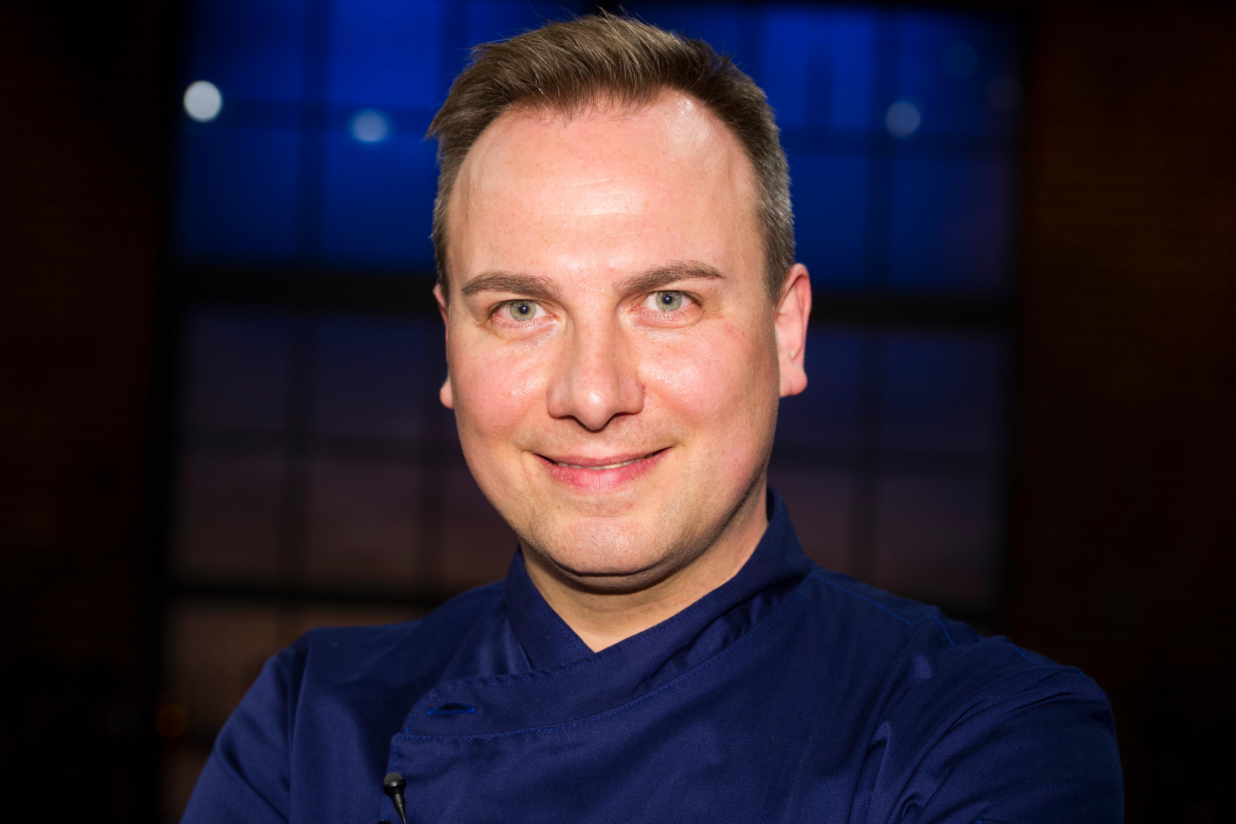 Tim Raue, Sternekoch, schaut in die Kamera und lächelt.