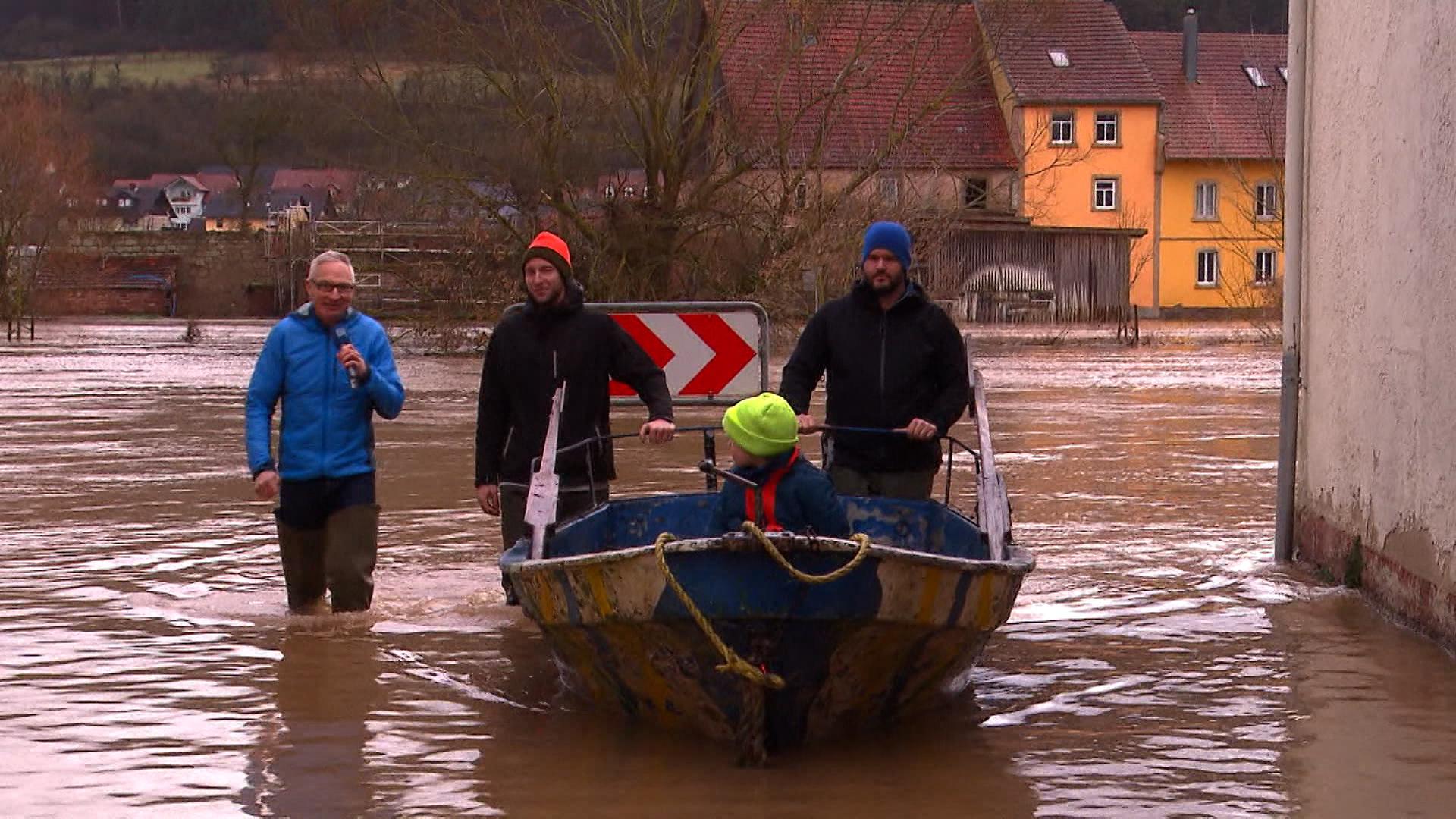Personen mit Boot laufen durch überflutete Straße