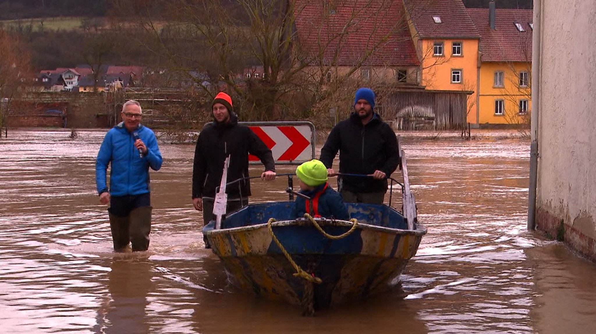 Personen mit Boot laufen durch überflutete Straße