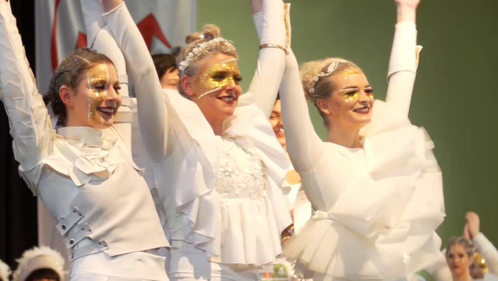 Tänzerinnen der Tanzgarde Soul City Dancers aus Hof in weißen Kostümen strecken die Arme in die Höhe. 