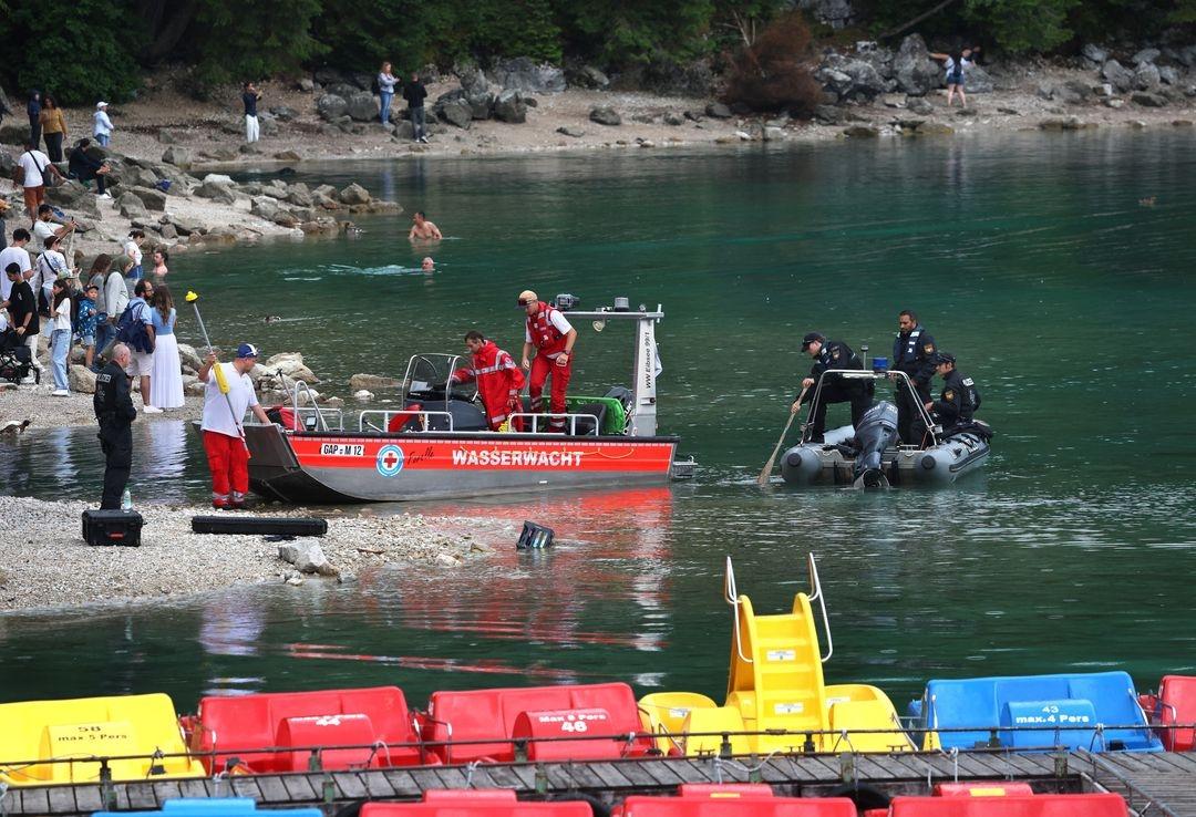 Rettungskräfte von Polizei und Wasserwacht legen hinter den Tretbooten eines geschlossenen Bootsverleihs am Ufer des Eibsees an.