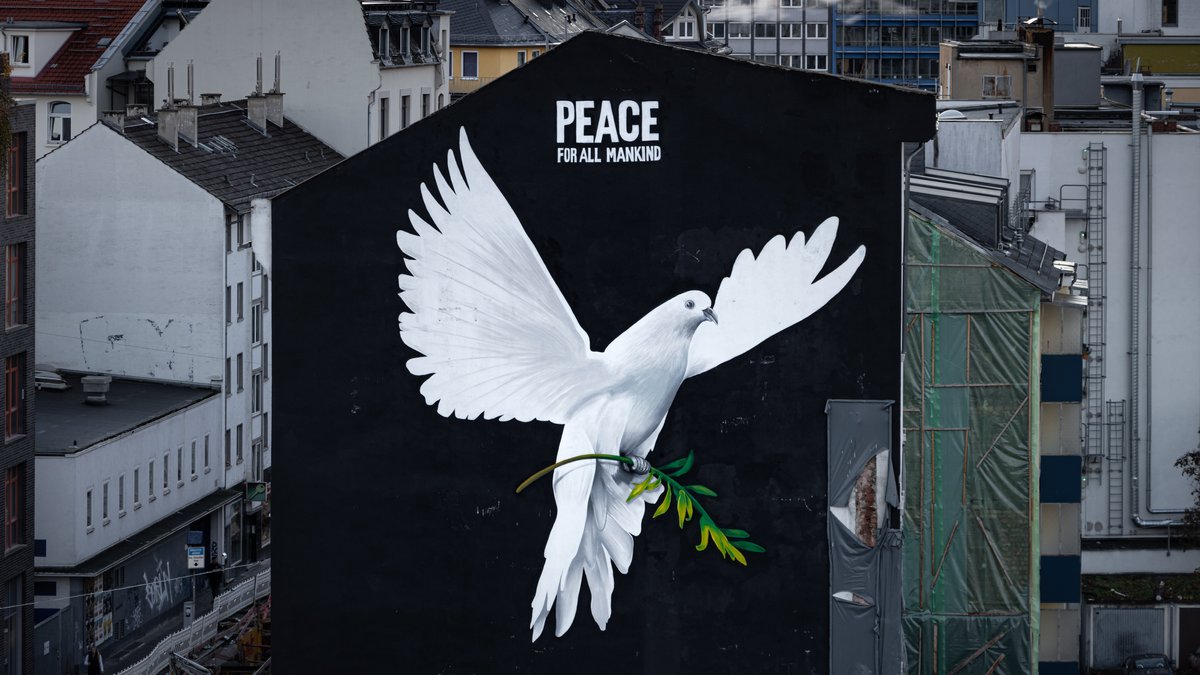 "PEACE FOR ALL MANKIND" (Frieden für die ganze Menschheit) steht über dem Bild einer riesigen Friedenstaube an einer Hauswand in Frankfurt am Main