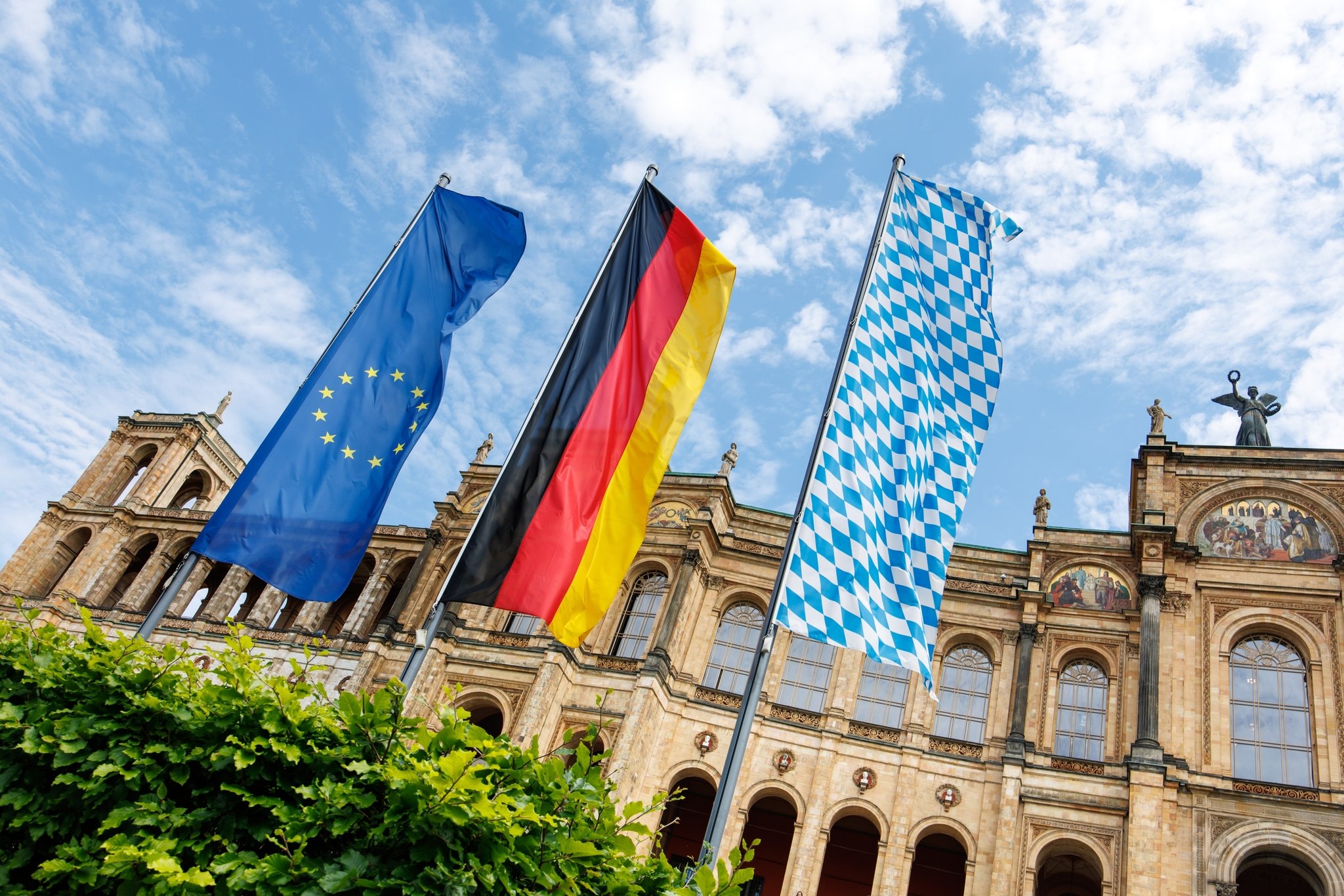 (Archivbild) Die europäische, die deutsche und die bayerische Flagge wehen vor dem Maximilianeum, Sitz des Bayerischen Landtags.