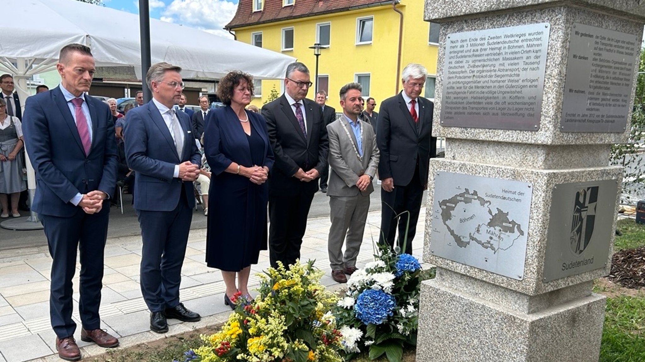 Menschen stehen vor einer steinernen Gedenktafel und haben die Hände gefaltet. | Bild: BR/Anne Axmann Menschen stehen vor einer steinernen Gedenktafel und haben die Hände gefaltet.