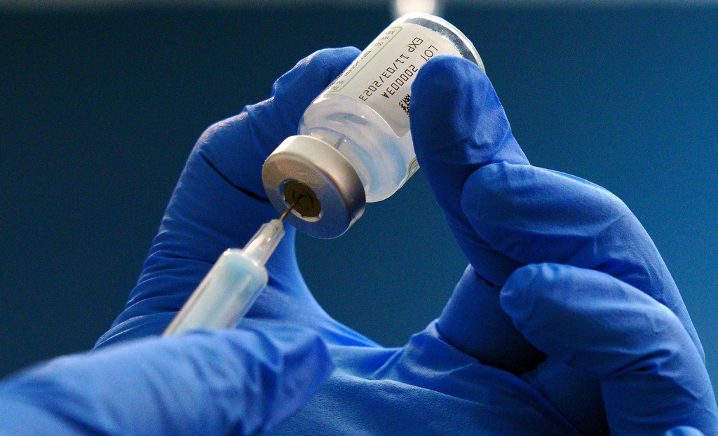 Mitarbeiter eines Gesundheitszentrums in England zieht Spritze mit einem der neuen, an die Omikron-Varianten angepassten Impfstoffe auf.