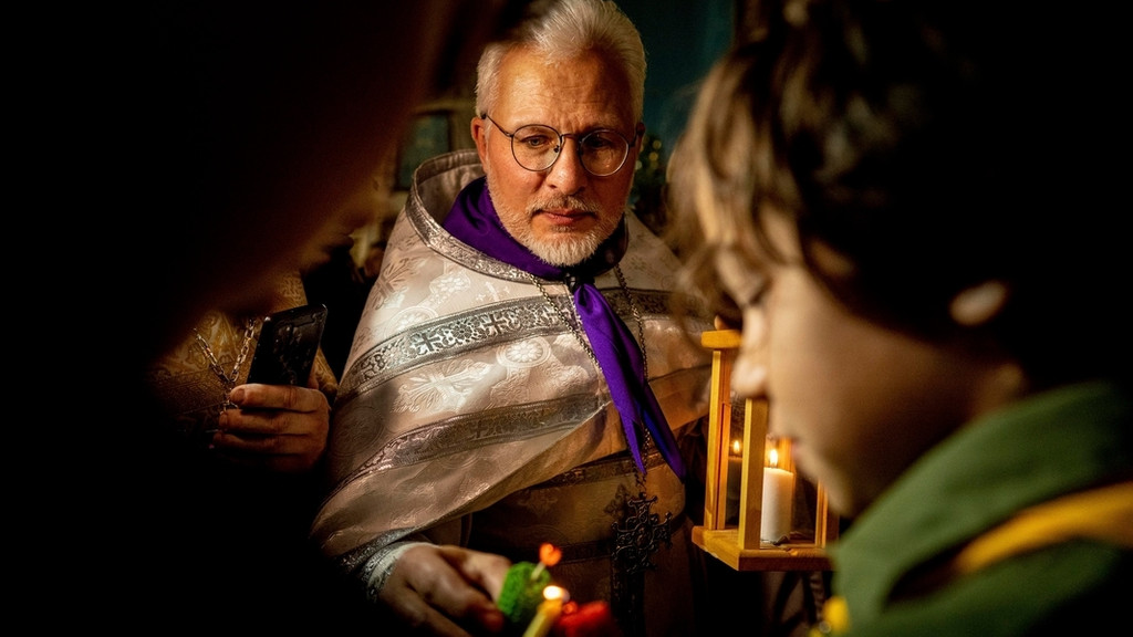 Ein orthodoxer Priester erhält während eines Weihnachtsgottesdienstes ein Friedenslicht aus Bethlehem.