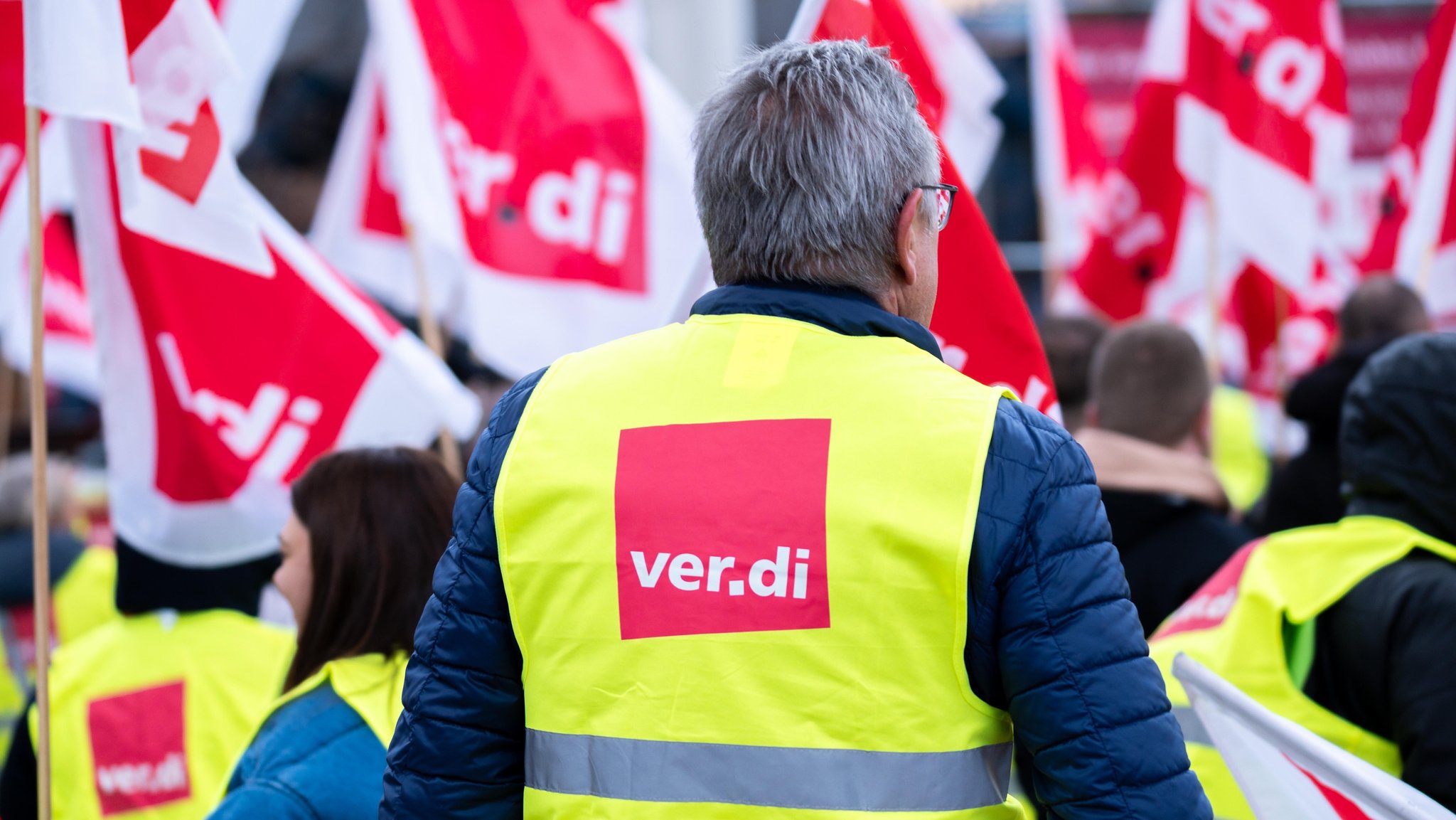(Archivbild) Mitarbeiter im öffentlichen Dienst bei der Kundgebung der Gewerkschaft mit Warnwesten und Fahnen von Ver.di.