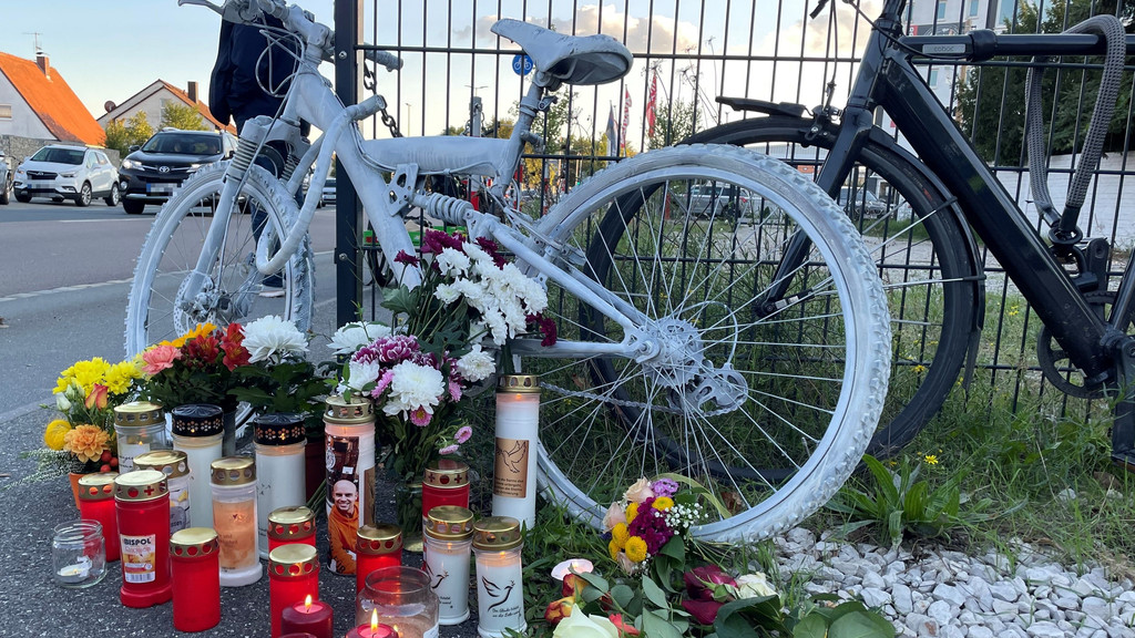 Weißes Ghost Bike mit Kerzen und Blumen