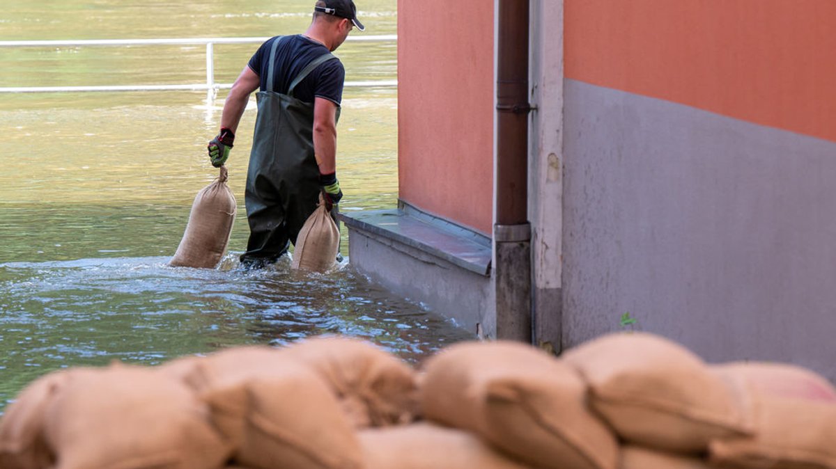 Ein Mann trägt in Passau Sandsäcke zum Abdichten von Türen und Fenstern durch das Hochwasser der Donau. (Archivbild)