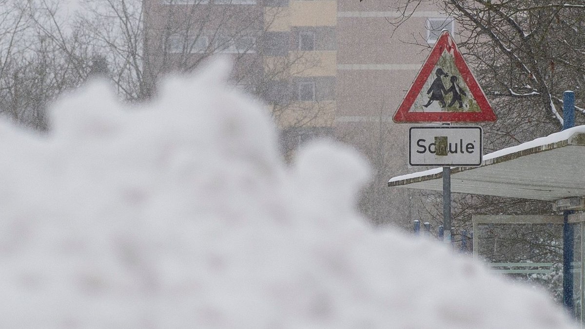 Ein Schneeberg liegt vor einem Verkehrszeichen einer Schule (Archivbild).