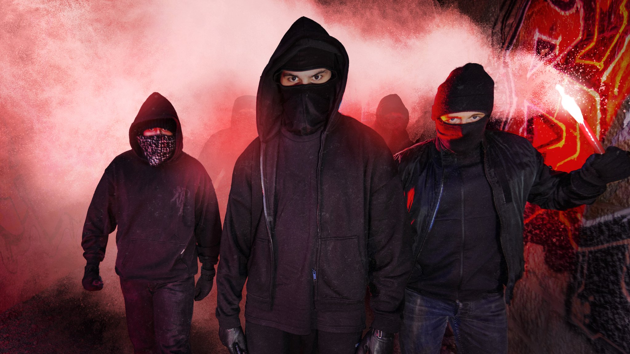 (Symbolbild) Eine Gruppe vermummter Männer zwischen Pyrolicht und Rauch.