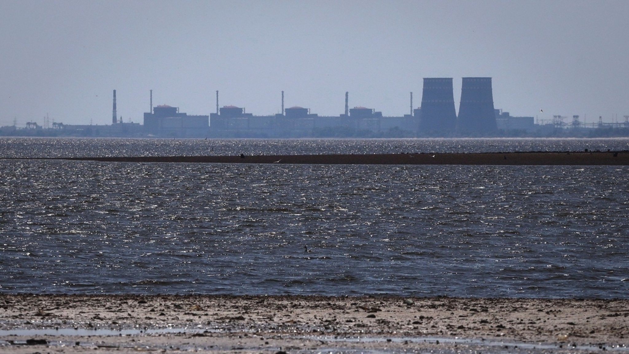 Archivbild von 2023: Das Kernkraftwerk Saporischschja ist im Hintergrund des flachen Kachowka-Stausees nach der Zerstörung des Staudamms zu sehen. | Bild: dpa-Bildfunk/Kateryna Klochko Archivbild von 2023: Das Kernkraftwerk Saporischschja ist im Hintergrund des flachen Kachowka-Stausees nach der Zerstörung des Staudamms zu sehen.