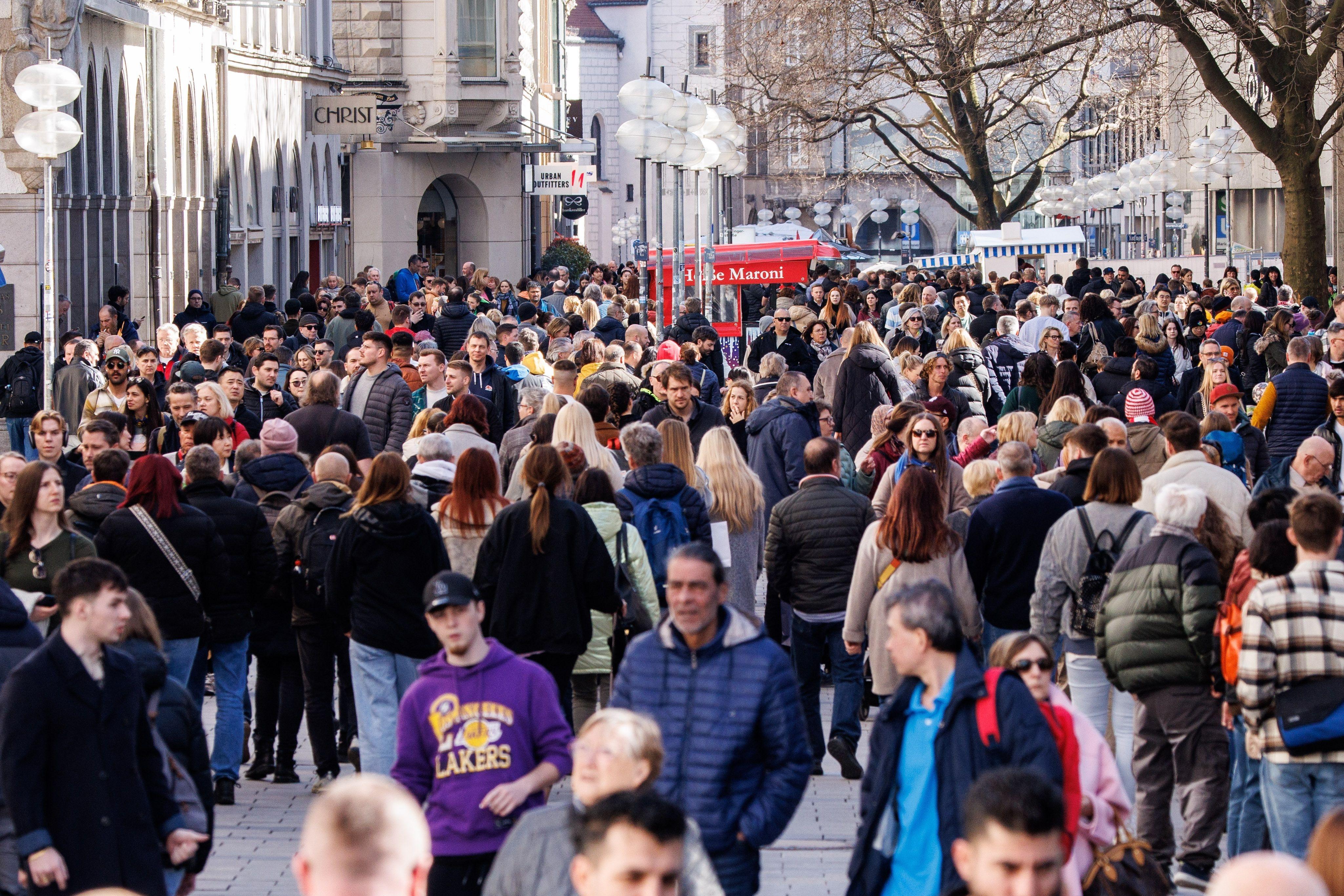 Menschen gehen in der Innenstadt von München an Geschäften an der Kaufingerstraße vorüber.