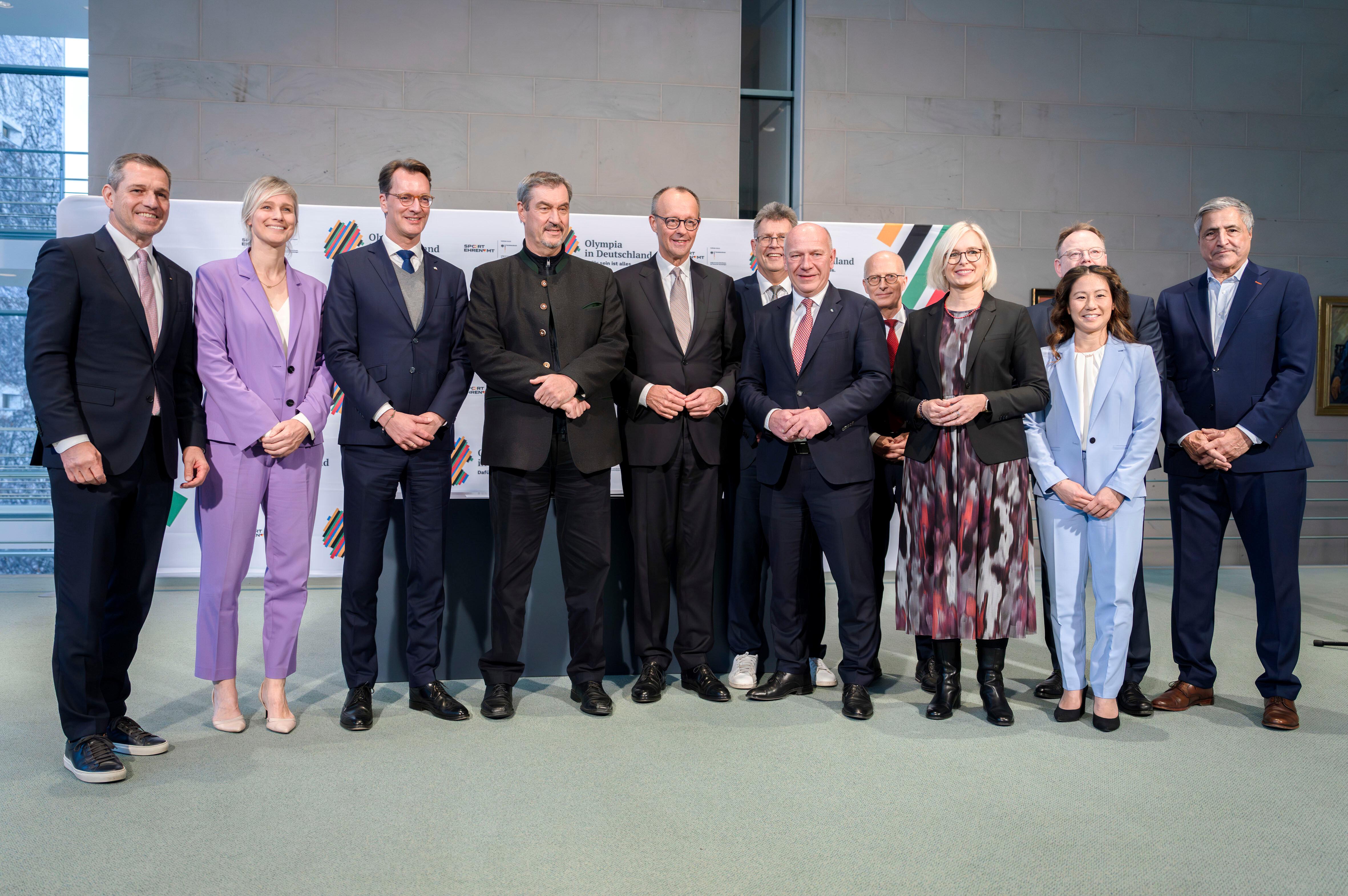 Michael Mronz, Britta Heidemann, Hendrik Wüst, Markus Söder, Friedrich Merz, Kai Wegner, Thomas Weikert, Peter Tschentscher, Christiane Schenderlein, Torsten Burmester, Kim Bui und Kaweh Niroomand bei der Unterzeichnung der Vereinbarung zur Olympiabewerbung im Bundeskanzleramt.