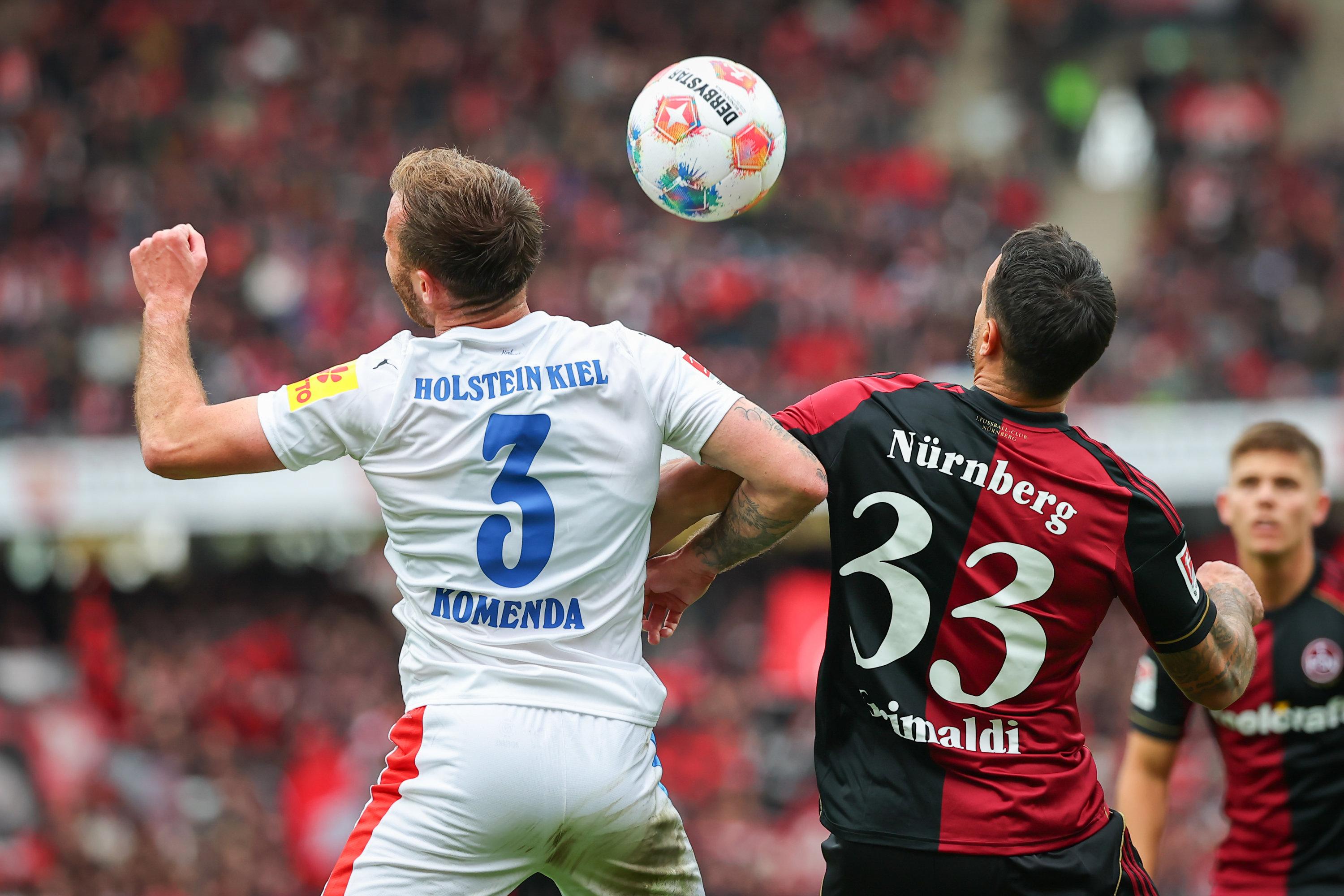 19.10.2025, Bayern, Nürnberg: Fußball: 2. Bundesliga, 1. FC Nürnberg - Holstein Kiel, 9. Spieltag im Max-Morlock-Stadion. Adriano Gimaldi (1. FC Nürnberg, r) und Marco Komenda (Holstein Kiel) kämpfen um den Ball. 