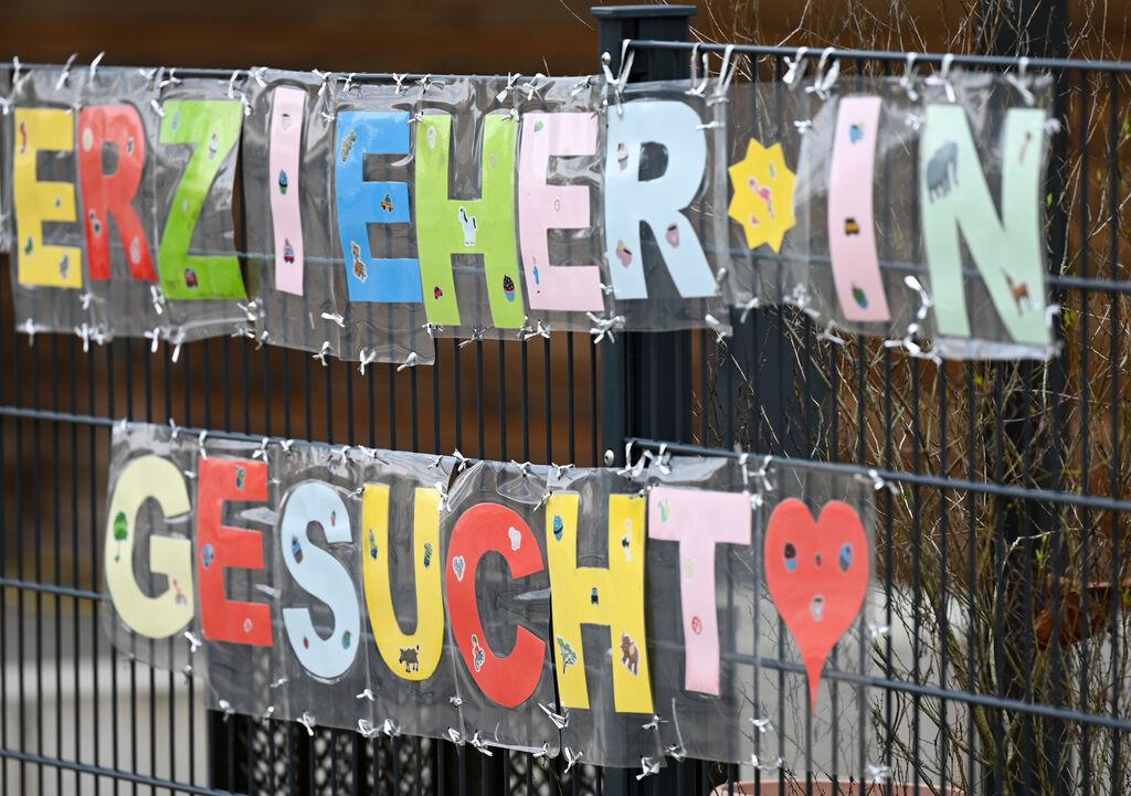 ILLUSTRATION - 10.02.2023, Hessen, Frankfurt/Main: Mit bunten Buchstaben sind die Worte ·Erzieher*in gesucht· geformt, die an einem Zaun einer Kindertagesstätte im Stadtteil Sachsenhausen befestigt sind.  (zu dpa: «Alle Fraktionen im Landtag wollen frühkindliche Bildung ausbauen») Foto: Arne Dedert/dpa +++ dpa-Bildfunk +++