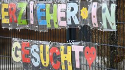 ILLUSTRATION - 10.02.2023, Hessen, Frankfurt/Main: Mit bunten Buchstaben sind die Worte ·Erzieher*in gesucht· geformt, die an einem Zaun einer Kindertagesstätte im Stadtteil Sachsenhausen befestigt sind.  (zu dpa: «Alle Fraktionen im Landtag wollen frühkindliche Bildung ausbauen») Foto: Arne Dedert/dpa +++ dpa-Bildfunk +++ | Bild:dpa-Bildfunk/Arne Dedert