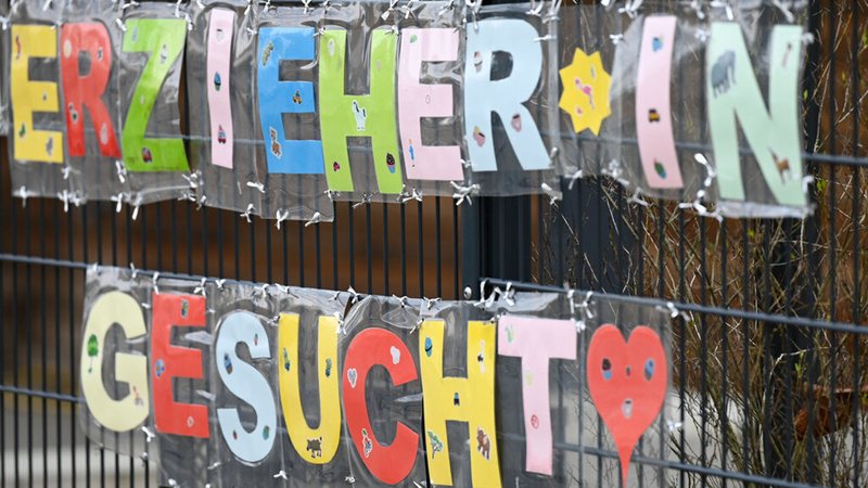 ILLUSTRATION - 10.02.2023, Hessen, Frankfurt/Main: Mit bunten Buchstaben sind die Worte ·Erzieher*in gesucht· geformt, die an einem Zaun einer Kindertagesstätte im Stadtteil Sachsenhausen befestigt sind.  (zu dpa: «Alle Fraktionen im Landtag wollen frühkindliche Bildung ausbauen») Foto: Arne Dedert/dpa +++ dpa-Bildfunk +++