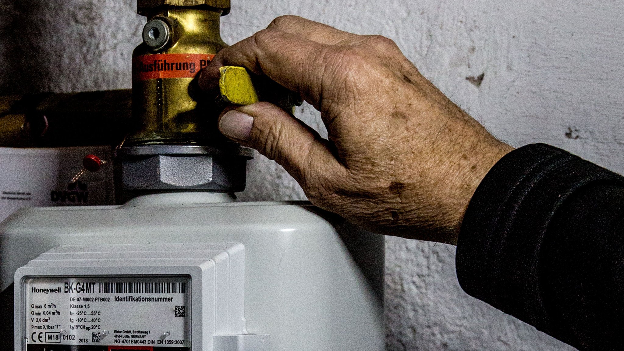 Eine Person dreht im Wohnhaus den Haupthahn der Erdgaszuleitung für die Gasheizung des Hauses ab.