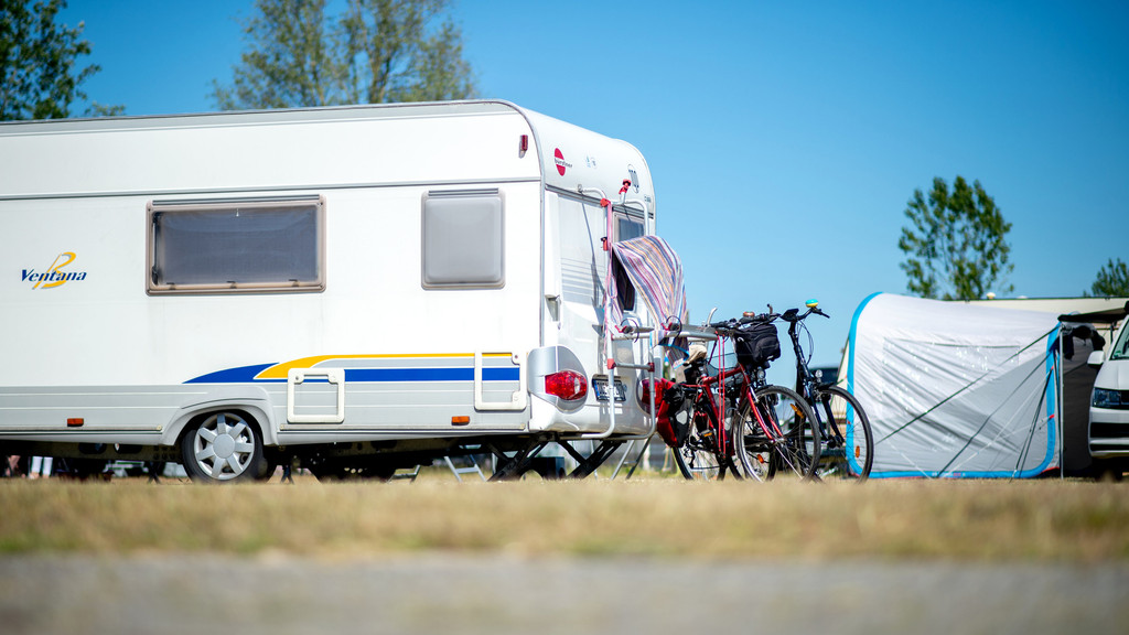 Fahrräder stehen auf einem Campingplatz neben einem Wohnwagen. 